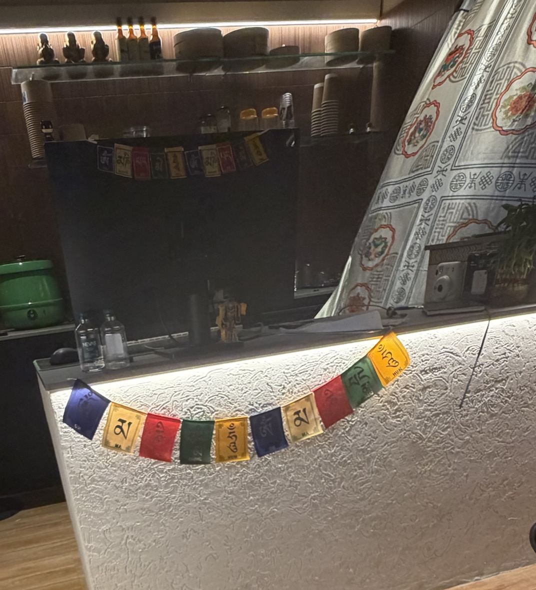 The order counter with prayer flags, bamboo steamers and shelves behind