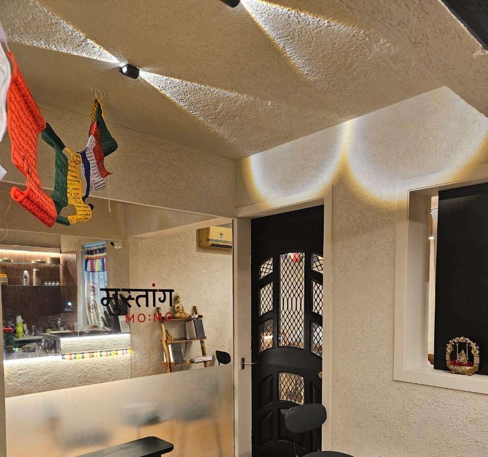 Café interior with prayer flags, black door and the Devanagari Mustang sign behind glass