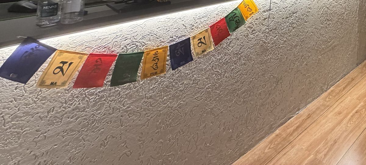 Prayer flags strung along the textured plaster counter, lit from above